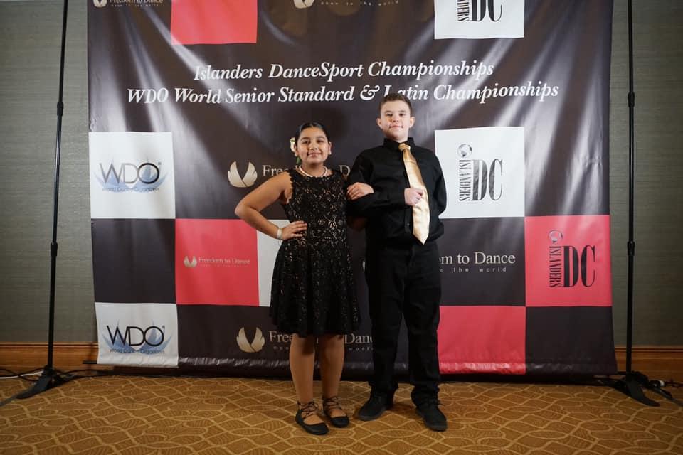 boy and girl standing in front of the Islander DanceSport Championship Banner