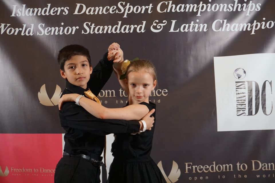 boy and girl standing in front of the Islander DanceSport Championship Banner in Dance pose
