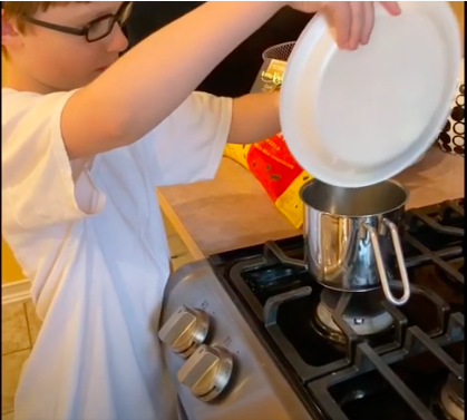 boy pouring ingredients into a pot